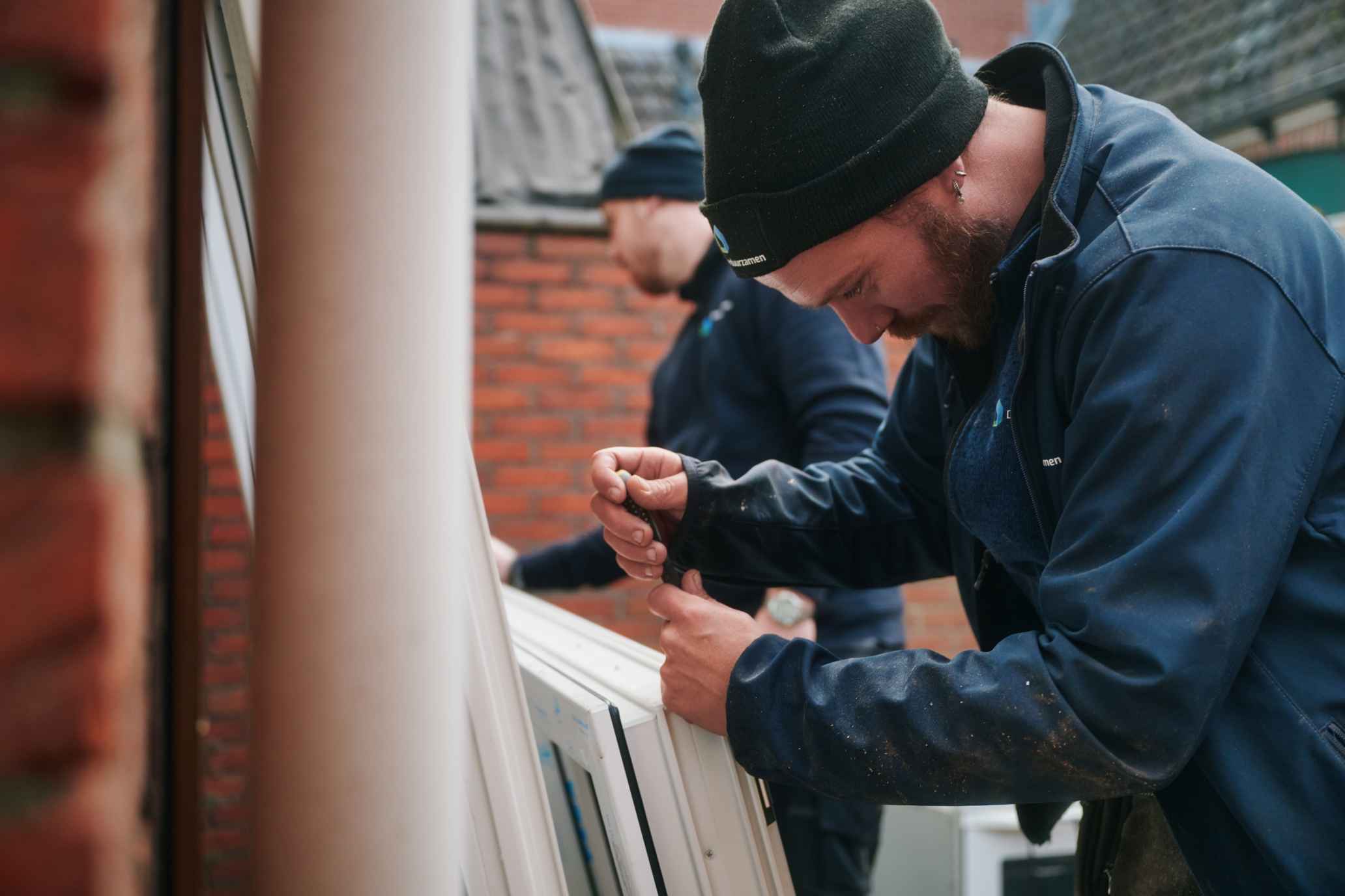 Monteur van Direct Verduurzamen bevestigt een nieuw wit kunststof kozijn
