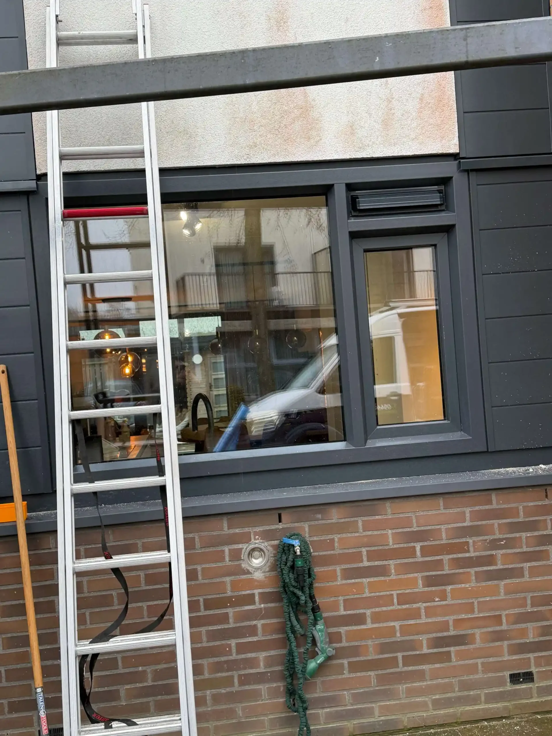 Ladder tegen een gevel met nieuwe antraciet kunststof kozijnen op de verdieping