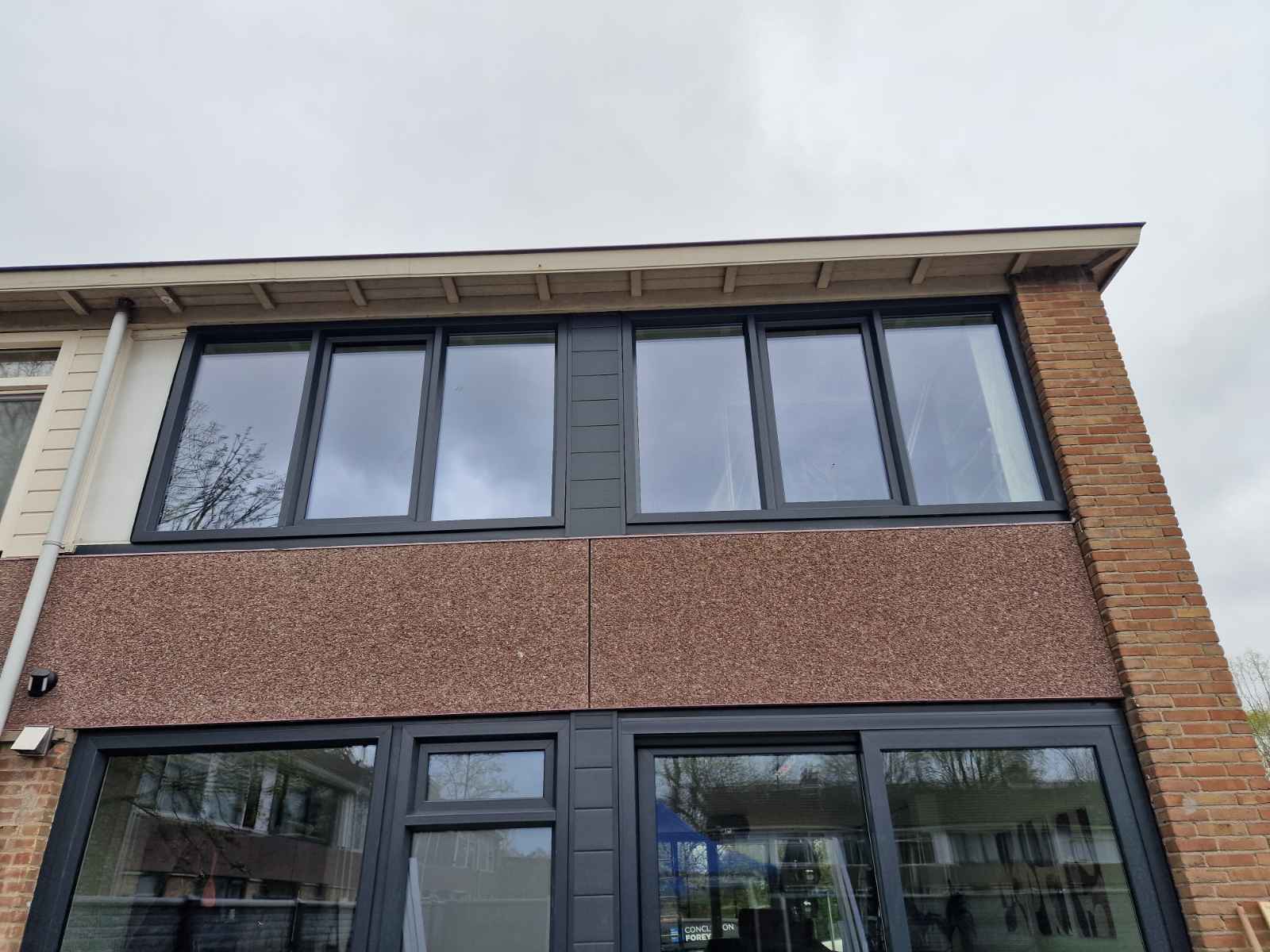 Achtergevel met grote antraciet kunststof kozijnen op de begane grond en de verdieping